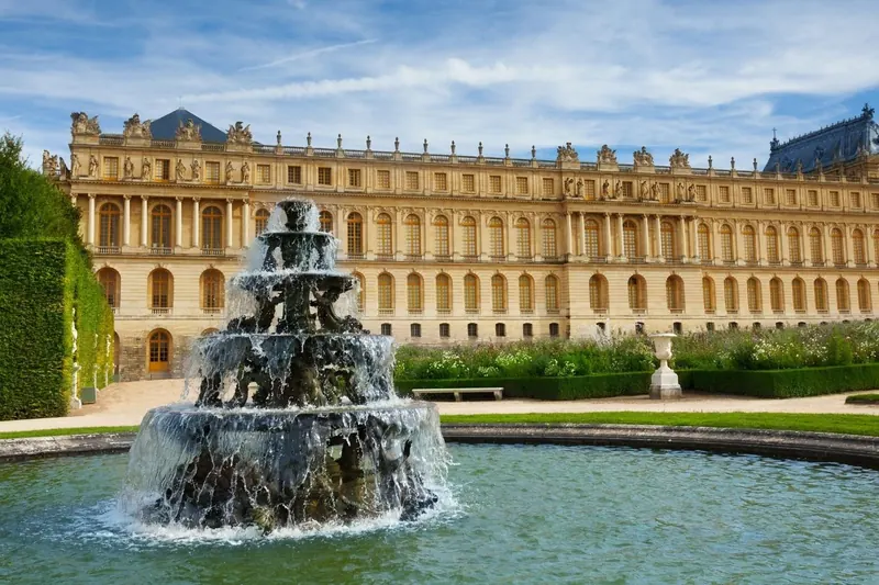 Tiered garden fountain in front of the Palace of Versailles garden facade on a clear day