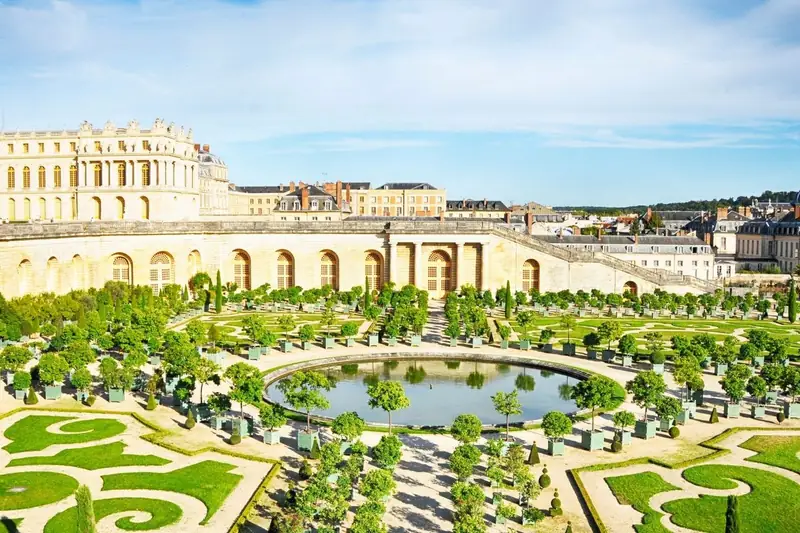 Versailles Orangerie gardens from above with circular pool, parterres and the palace beyond